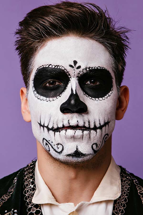 Man wearing half skeleton day of the dead makeup