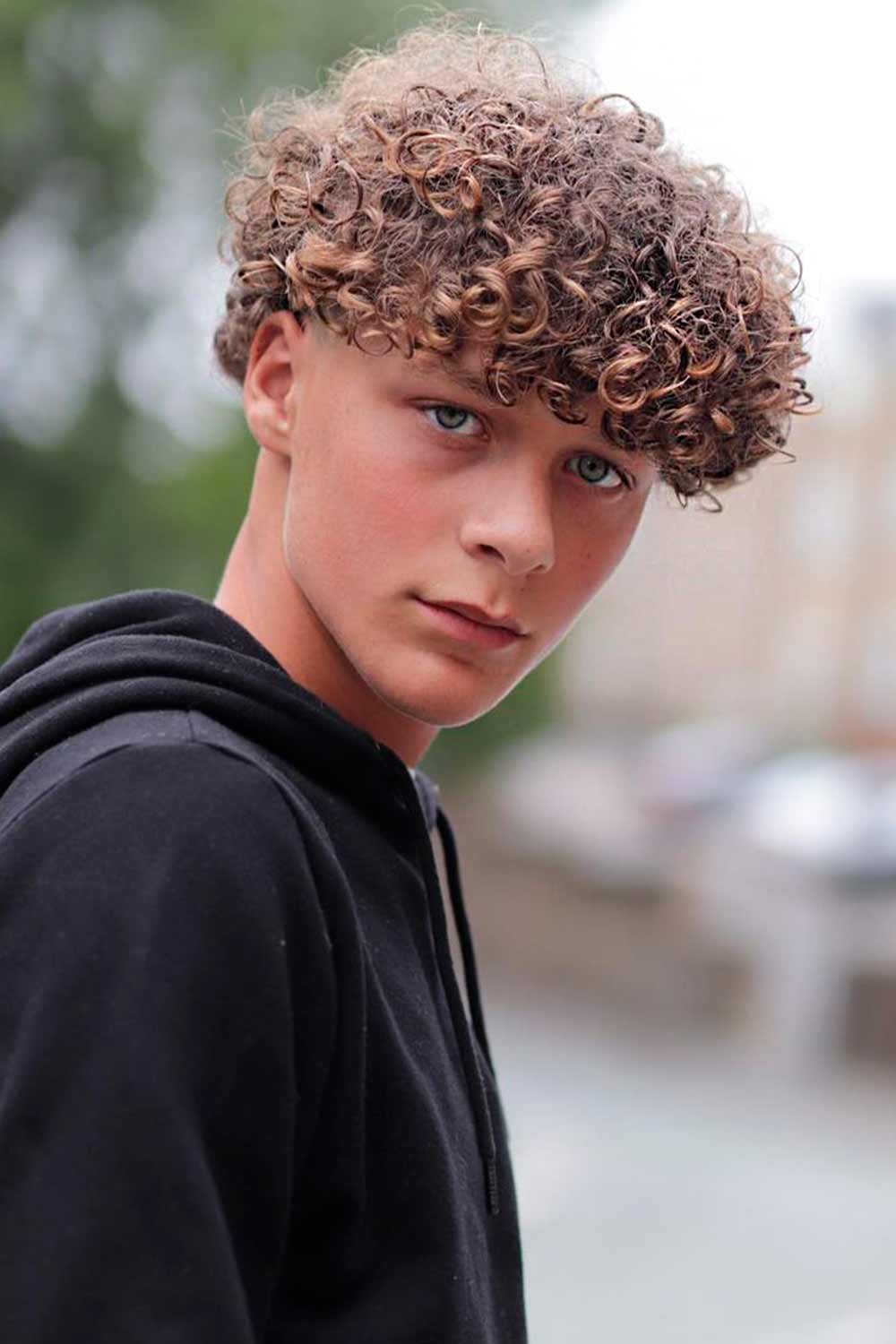 Young bearded man model of fashion sitting in an urban step wearing  casual clothes Guy with beard and modern hairstyle looking away in the  street Stock Photo  Alamy